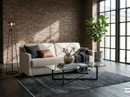 Hovden Victory 160 sovesofa i lyst tekstil foran røff mursteinsvegg. Eksklusiv 160 cm sovesofa med 17 cm pocketmadras – perfekt til loft eller urbane hjem.