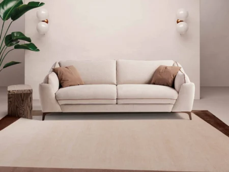 Klassisk moderne sovesofa med myke puter sett rett forfra i et koselig stuemiljø.