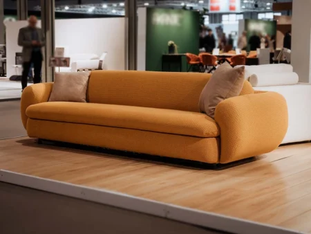 Profilbilde av Curvi sovesofa i et klart oransje tekstil. Designet skiller seg ut med sine unike kurver og har høy sittekomfort med memory foam.