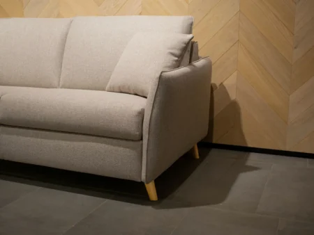Detaljvisning av Valentina sovesofa med beige stoff og treben. En sjelden sovesofa-modell som tillater støvsuging under sofaen